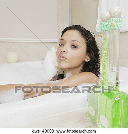 Stock Photo - Portrait of a teenage girl scrubbing her back in the bathtub. Fotosearch