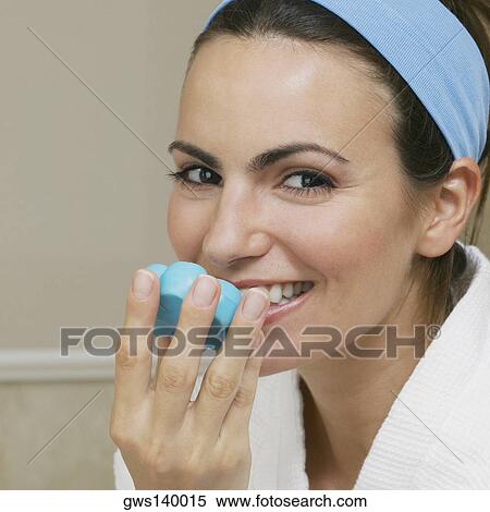 Stock Photography - Portrait of a young woman smelling a bar of soap. Fotosearch