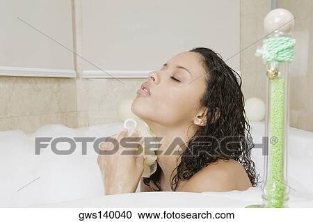 Side profile of a teenage girl scrubbing her body in the bathtub View Large Photo Image Stock Image - Side profile of a teenage girl scrubbing her body in the bathtub. Fotosearch