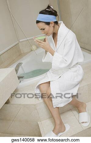 Side profile of a young woman sitting near a bathtub and smelling a dish of bath crystals View Large Photo Image Stock Photo - Side profile of a young woman sitting near a bathtub and smelling a dish of bath crystals. Fotosearch