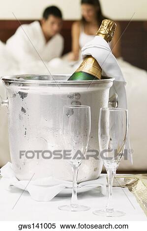 Stock Photography - Close-up of a champagne bottle in an ice bucket with two champagne flutes. Fotosearch