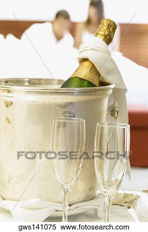 Stock Photography - Close-up of a champagne bottle in an ice bucket with two champagne flutes. Fotosearch