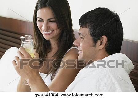 Picture - Close-up of a young woman and a mid adult man toasting with champagne flutes. Fotosearch