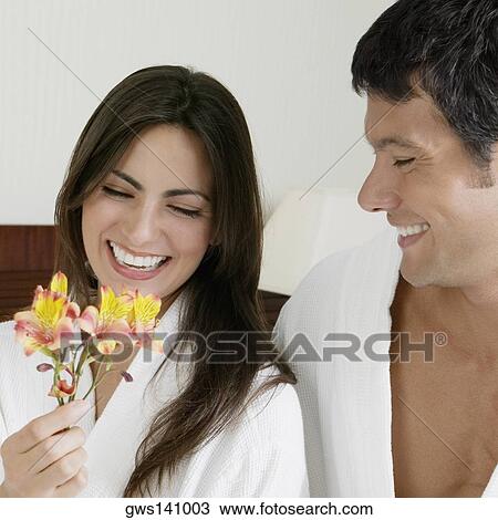 Stock Image - Close-up of a young woman and a mid adult man looking at flowers. Fotosearch