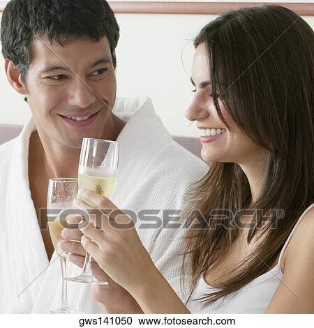 Stock Image - Close-up of a young woman and a mid adult man toasting with champagne flutes. Fotosearch