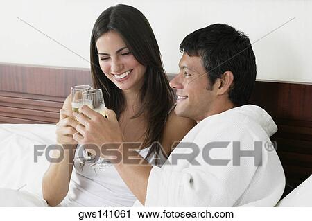 Stock Image - Close-up of a young woman and a mid adult man toasting with champagne flutes. Fotosearch