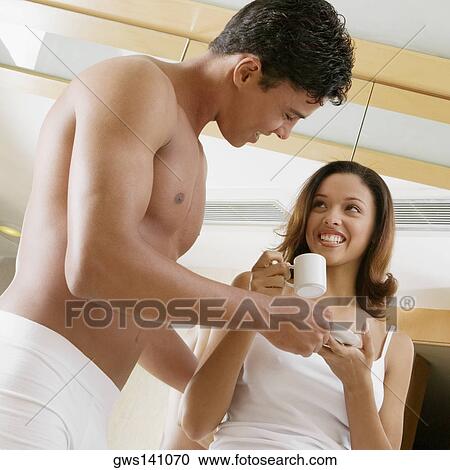 Stock Image - Low angle view of a teenage girl holding a tea cup with a young man looking at her. Fotosearch