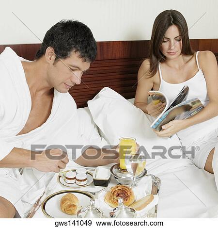 Mid adult man having breakfast with a young woman reading a magazine View Large Photo Image Stock Photo - Mid adult man having breakfast with a young woman reading a magazine. Fotosearch
