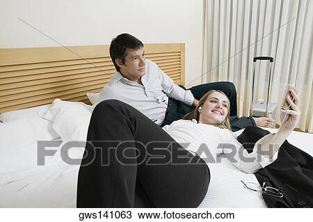Mid adult man lying on the bed with a young woman listening to an MP3 player View Large Photo Image Stock Image - Mid adult man lying on the bed with a young woman listening to an MP3 player. Fotosearch