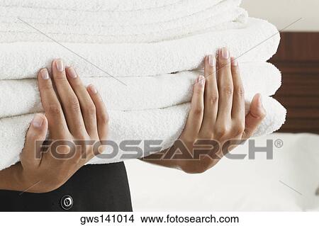 Mid section view of a woman holding a stack of towels View Large Photo Image Picture - Mid section view of a woman holding a stack of towels. Fotosearch