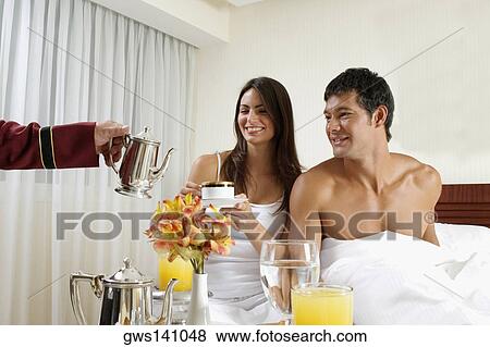 Person's hand serving tea to a young woman and a mid adult man on the bed View Large Photo Image Stock Photo - Person's hand serving tea to a young woman and a mid adult man on the bed. Fotosearch