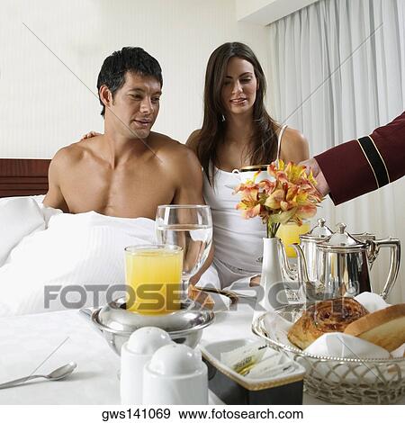 Person's hand serving tea to a young woman and a mid adult man on the bed View Large Photo Image Stock Photo - Person's hand serving tea to a young woman and a mid adult man on the bed. Fotosearch