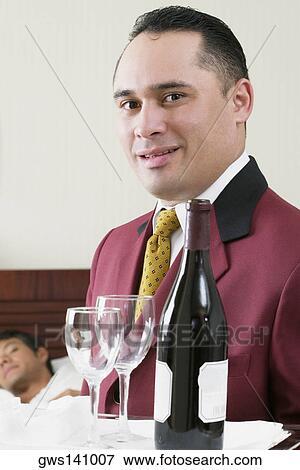 Portrait of a waiter holding a tray with a wine bottle and two wineglasses View Large Photo Image Stock Photo - Portrait of a waiter holding a tray with a wine bottle and two wineglasses. Fotosearch