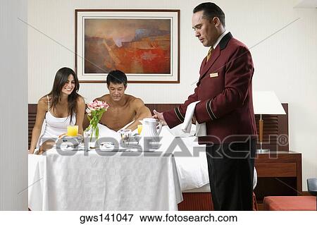 Side profile of a waiter serving a young woman and a mid adult man breakfast in bed View Large Photo Image Stock Photo - Side profile of a waiter serving a young woman and a mid adult man breakfast in bed. Fotosearch