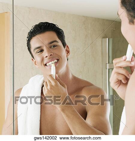 Close-up of a young man applying lip balm View Large Photo Image Stock Image - Close-up of a young man applying lip balm. Fotosearch