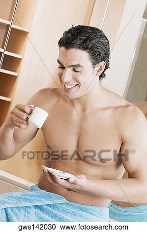 Stock Image - Close-up of a young man drinking a cup of tea. Fotosearch