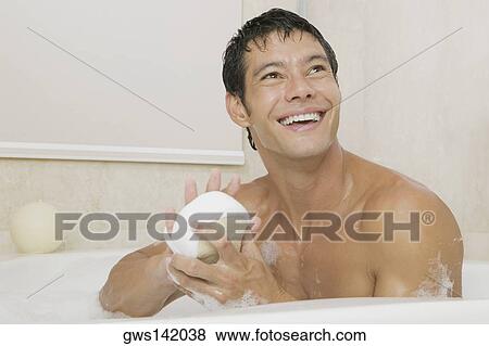 Close-up of a young man holding a loofah in a bathtub View Large Photo Image Stock Photo - Close-up of a young man holding a loofah in a bathtub. Fotosearch