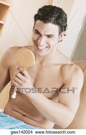 Picture - Close-up of a young man looking into a mirror. Fotosearch