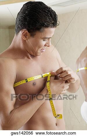 Close-up of a young man measuring his chest with a tape measure View Large Photo Image Stock Photograph - Close-up of a young man measuring his chest with a tape measure. Fotosearch
