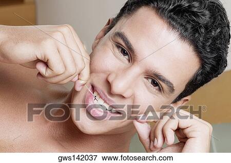 Stock Photo - Portrait of a young man flossing his teeth. Fotosearch