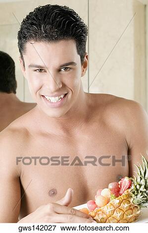 Portrait of a young man holding a plate of fruit View Large Photo Image Stock Photo - Portrait of a young man holding a plate of fruit. Fotosearch