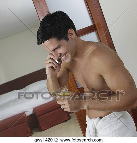 Side profile of a young man talking on a mobile phone and holding a glass of juice View Large Photo Image Stock Image - Side profile of a young man talking on a mobile phone and holding a glass of juice. Fotosearch
