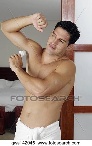 Young man applying deodorant under his armpit View Large Photo Image Stock Photography - Young man applying deodorant under his armpit. Fotosearch