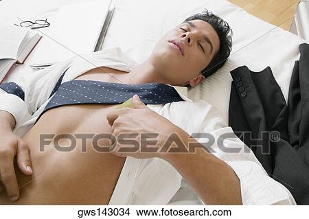 Picture - High angle view of a businessman sleeping on the bed. Fotosearch