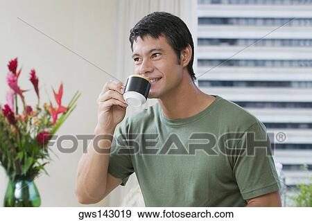 Stock Photo - Mid adult man drinking a cup of tea. Fotosearch