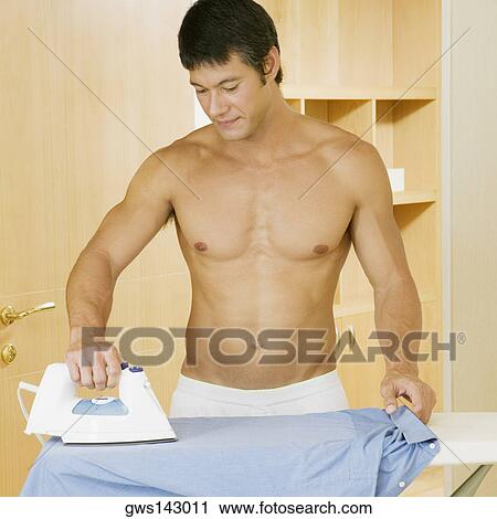 Mid adult man ironing a shirt on an ironing board View Large Photo Image Stock Image - Mid adult man ironing a shirt on an ironing board. Fotosearch
