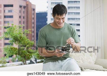 Mid adult man stirring tea with a teaspoon View Large Photo Image Stock Photo - Mid adult man stirring tea with a teaspoon. Fotosearch