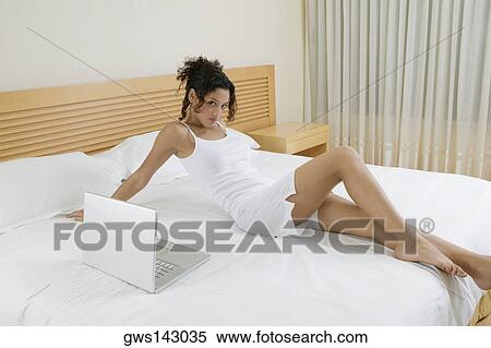 Portrait of a teenage girl reclining on the bed beside a laptop View Large Photo Image Stock Photography - Portrait of a teenage girl reclining on the bed beside a laptop. Fotosearch