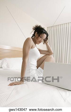 Portrait of a teenage girl sitting on the bed beside a laptop View Large Photo Image Stock Photo - Portrait of a teenage girl sitting on the bed beside a laptop. Fotosearch