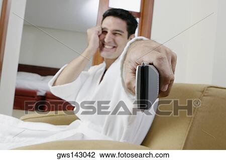 Portrait of a young man using a remote control and smiling View Large Photo Image Stock Image - Portrait of a young man using a remote control and smiling. Fotosearch