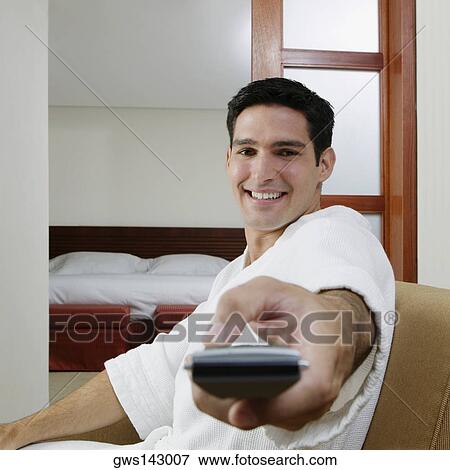 Portrait of a young man using a remote control and smiling View Large Photo Image Stock Photo - Portrait of a young man using a remote control and smiling. Fotosearch