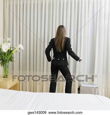 Rear view of a businesswoman standing with a suitcase View Large Photo Image Stock Photo - Rear view of a businesswoman standing with a suitcase. Fotosearch
