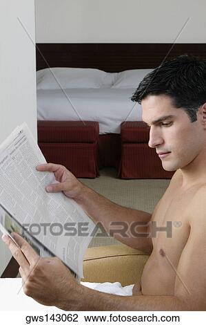 Stock Image - Side profile of a young man reading a newspaper. Fotosearch