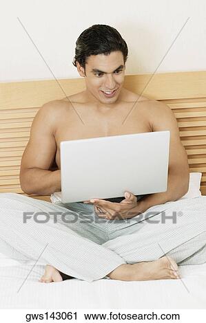 Young man using a laptop View Large Photo Image Stock Image - Young man using a laptop. Fotosearch