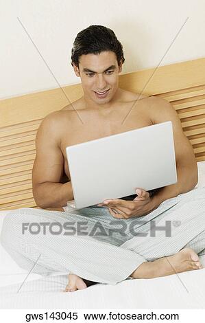 Young man using a laptop View Large Photo Image Stock Photography - Young man using a laptop. Fotosearch