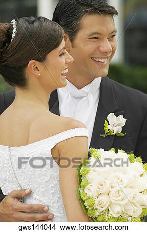 Close-up of a groom embracing his bride and smiling View Large Photo Image Picture - Close-up of a groom embracing his bride and smiling. Fotosearch