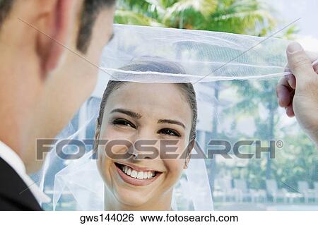 Stock Photograph - Close-up of a groom lifting his bride's veil. Fotosearch
