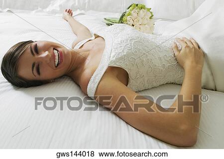 High angle view of a bride lying on the bed and smiling View Large Photo Image Stock Photo - High angle view of a bride lying on the bed and smiling. Fotosearch