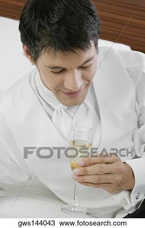 Stock Image - High angle view of a mid adult man holding a champagne flute. Fotosearch
