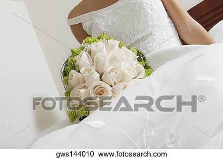 Mid section view of a bride lying on the bed and holding a bouquet of flowers View Large Photo Image Stock Image - Mid section view of a bride lying on the bed and holding a bouquet of flowers. Fotosearch