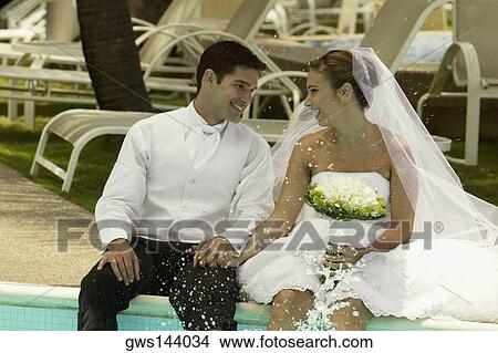 Newlywed couple sitting at the poolside and smiling View Large Photo Image Picture - Newlywed couple sitting at the poolside and smiling. Fotosearch