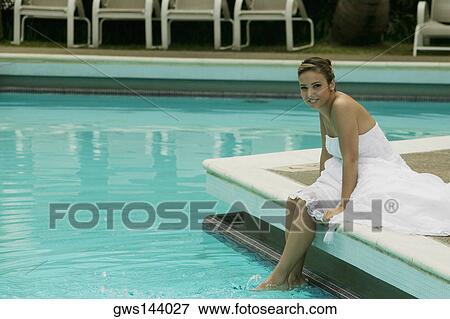Portrait of a bride sitting at the poolside with her feet in water View Large Photo Image Stock Photo - Portrait of a bride sitting at the poolside with her feet in water. Fotosearch