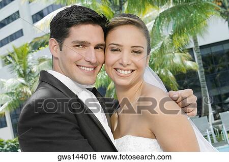 Stock Photograph - Portrait of a newlywed couple embracing each other. Fotosearch