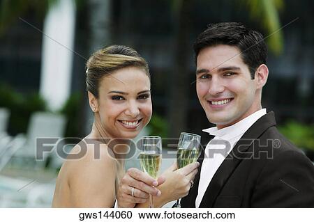 Portrait of a newlywed couple holding champagne flutes and smiling View Large Photo Image Stock Image - Portrait of a newlywed couple holding champagne flutes and smiling. Fotosearch
