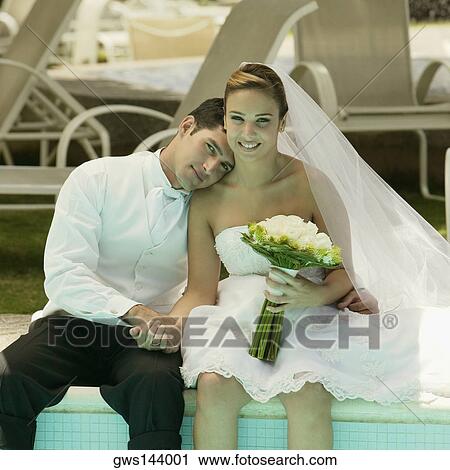 Portrait of a newlywed couple sitting at the poolside View Large Photo Image Stock Image - Portrait of a newlywed couple sitting at the poolside. Fotosearch