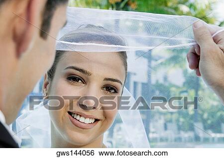 Stock Photograph - Rear view of a groom lifting his bride's veil. Fotosearch